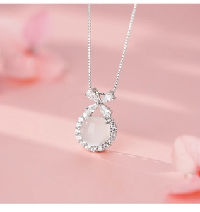 Macro detail of silver necklace featuring a butterfly bow and white agate gemstone pendant