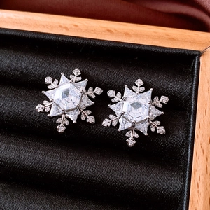 Macro shot of silver snowflake stud earrings with sparkling cubic zirconia on black velvet