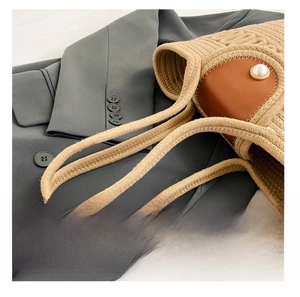 Detail of woven straw tote bag with brown leather accent and a white pearl button detail