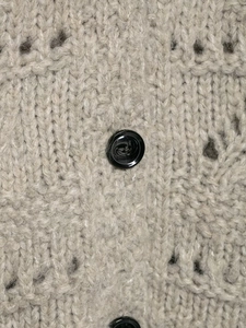 Close-up of taupe chunky knit cardigan texture with a polished black round button