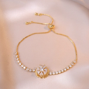 Detail of adjustable gold bracelet featuring a rotating petal charm and white zircons