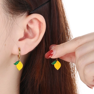 Créoles dorées avec pendentifs citrons en émail jaune portées par un mannequin