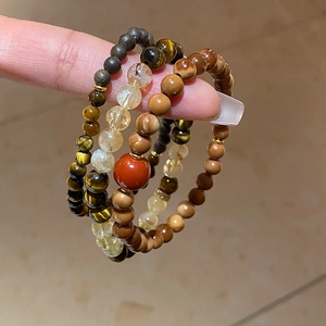 Detailed shot of Rutilated Quartz and Tiger Eye beaded bracelets with red accent bead