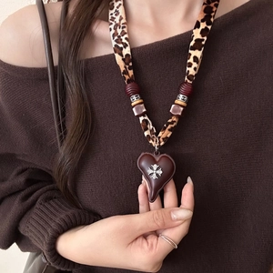 Detailed macro view of heart pendant with silver emblem and leopard print cord