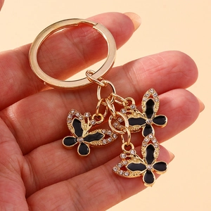 Detail of hand-held golden butterfly keychain with black enamel and clear rhinestones