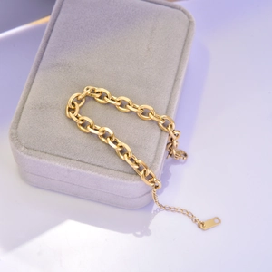 Detail view of a chunky gold oval link titanium steel bracelet on a jewelry box