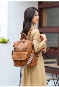 Close-up of vintage brown leather backpack featuring woven straps and multi-zipper detail
