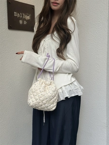 Detailed view of a white quilted floral drawstring storage bag carried by a model