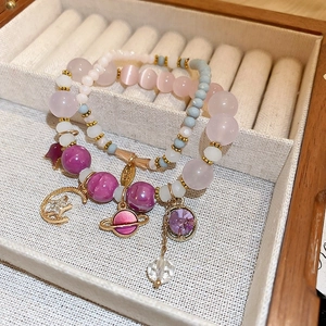 Detail of beaded bracelets with pink cat-eye stones, star charms and velvet jewelry box