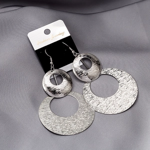 Detailed macro of silver triple layered geometric metal rings on grey silk fabric