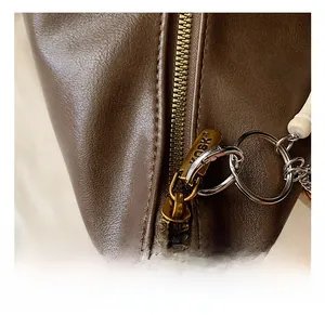 Detailed close-up of the vintage gold zipper and beads on a brown faux leather tote bag
