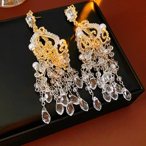 Detail of gold chandelier earrings with lace pattern, small pearls and crystal glass drops