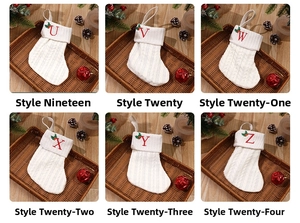 Close-up of white knitted Christmas stockings with red embroidered letters and holly details