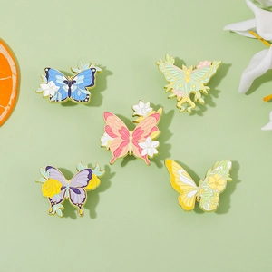 Detailed set of five colorful butterfly floral enamel pins on light green background