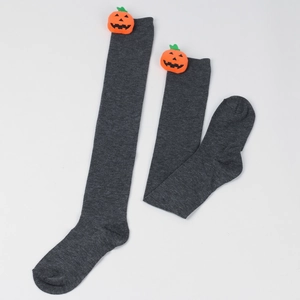 Detail of grey knitted over-knee socks with festive 3D pumpkin ornaments for Halloween