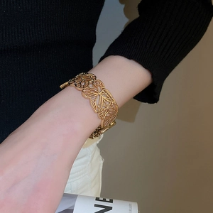 Detailed view of a gold hollow butterfly cuff bracelet on a female wrist