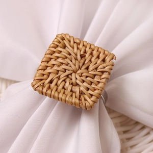Macro detail of handwoven natural rattan square napkin ring on a white linen cloth