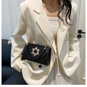 Detail view of black grained leather handbag with sparkling rhinestone starburst buckle