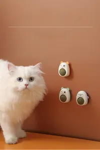 Long-haired cat playing with wall-mounted rotating catnip toys in bear and frog shapes
