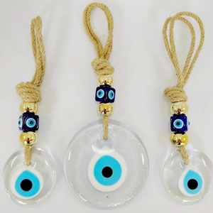 Three glass Evil Eye hanging ornaments with golden beads and jute rope on white background