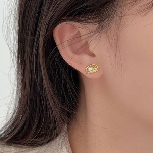 Close-up of shell shaped gold earrings with white pearl inlay worn by a female model