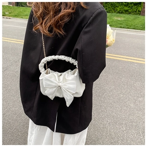 Detail of white cloud bag featuring a large bow and elegant pleated handle strap