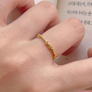 Minimalist 925 sterling silver bow ring in gold finish worn on hand with elegant background