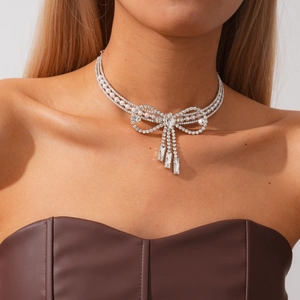 Detailed view of silver bow necklace with faux pearls, rhinestones and fringe tassels