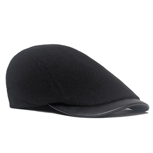 Detailed close-up of vintage black wool newsboy hat with faux leather brim and textured finish