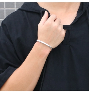 Close-up of a minimalist silver polished stainless steel open bangle on a model's wrist