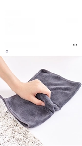 Gros plan d'un chiffon microfibre gris essuyant un plan de travail en marbre avec bord cousu