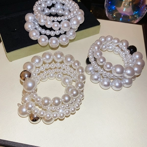 Close-up of multilayered pearl bracelets with silver and black bead accents on leather