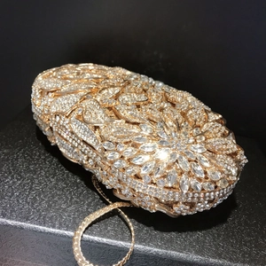 Close-up of golden leaf pattern evening clutch bag with sparkling rhinestones and chain