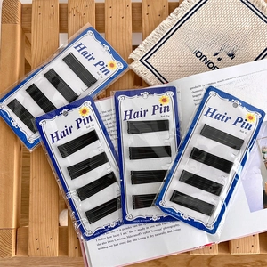 Classic black bobby pins with ball tips on a wooden background for women hair styling