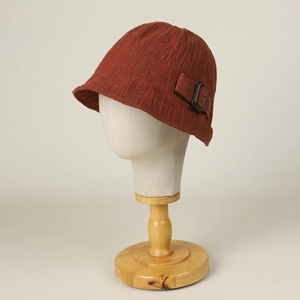 Deep brick red vintage linen cloche hat with textured fabric and metal buckle on mannequin