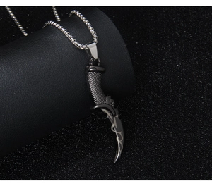 Detail of a dark metal grim reaper scythe pendant with textured handle on a box chain