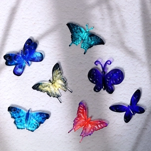 Sept pendentifs papillons en résine multicolore avec des ailes à relief sur fond blanc