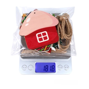 Detailed view of Christmas wooden house decorations set on a scale weighing 181.8g