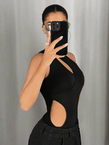 Detalle de body negro sin mangas con diseño de cortes asimétricos y pantalones vaqueros