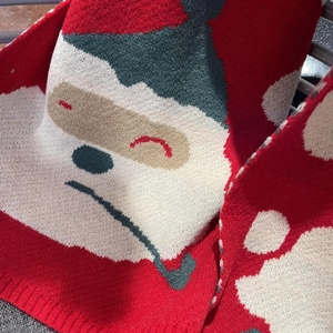 Close-up of a festive red knit snowman scarf with thick warm texture and holiday embroidery