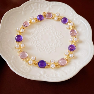 Detalle del choker vintage con gemas de resina púrpura y perlas sobre metal dorado