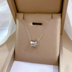 Macro detail of a silver cylinder pendant necklace inside a luxury jewelry display box