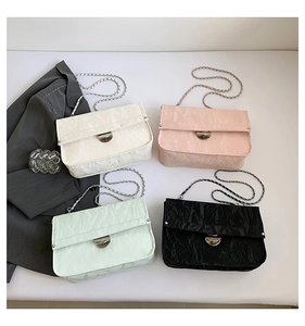 Detail view of four pleated leather chain bags in white, pink, green, and black colors