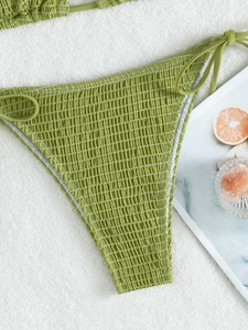 Detail of green smocked high waist bikini bottom with adjustable side ties and rich texture