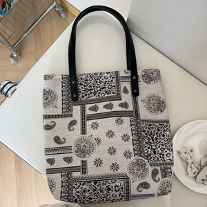 Close-up of vintage paisley print canvas tote bag with black leather handles and rivets