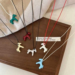 Close-up of colorful horse pendants in multiple finishes on a rustic wooden tray