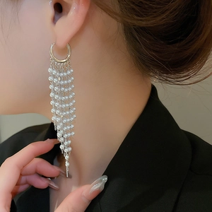 Detailed view of long pearl tassel earrings in silver finish worn by a model