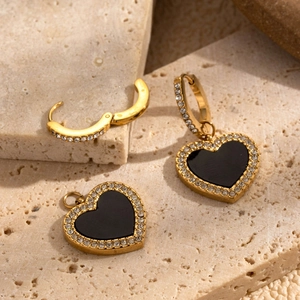 Boucles d'oreilles cœur doré avec incrustation noire et cristaux sur fond de pierre