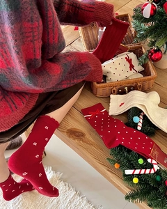 Detail of red Christmas socks with white bowknots and festive knit textures