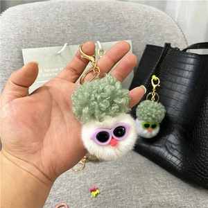 Close-up of fluffy cauliflower plush keychain with sunglasses on a black handbag